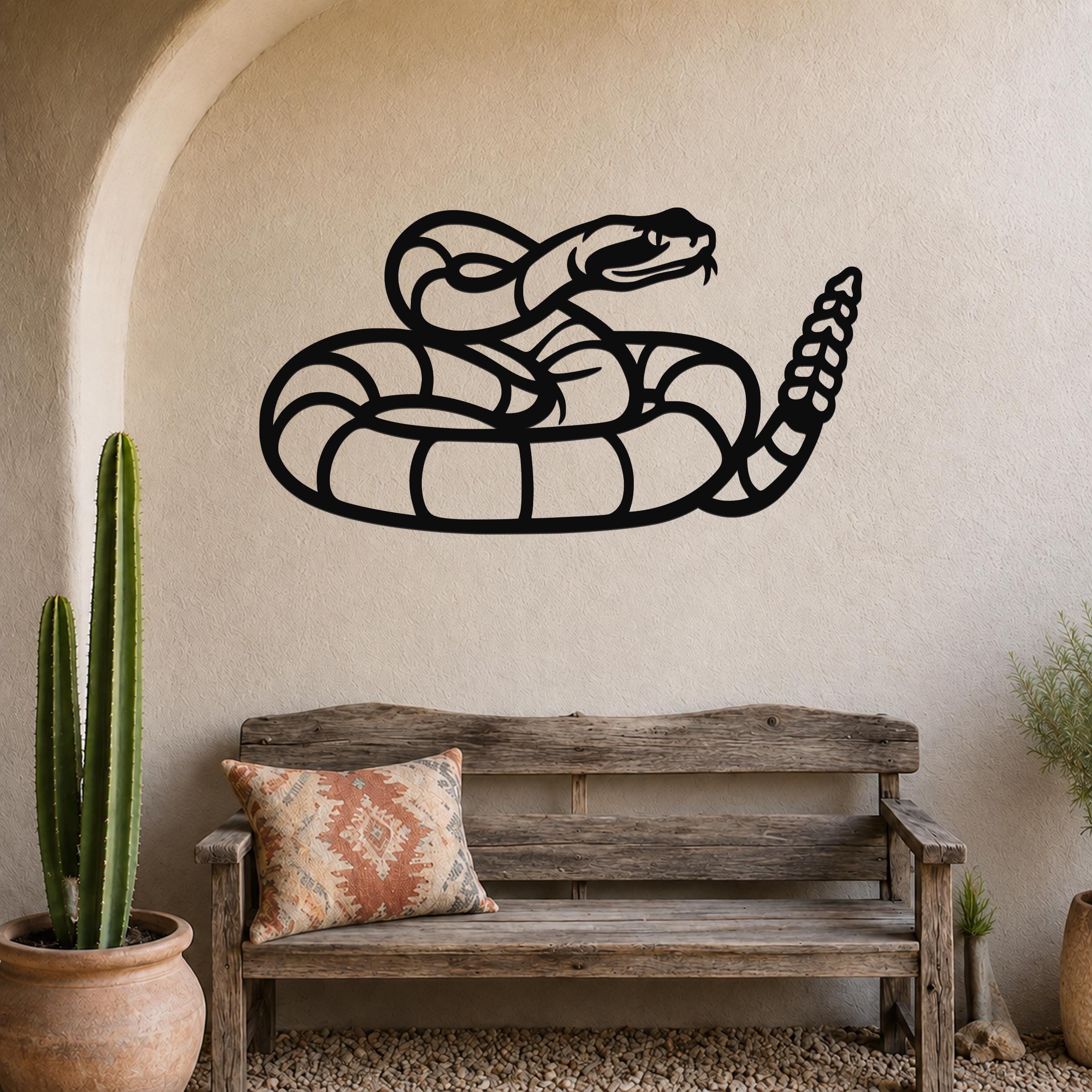 Black metal snake wall art with coiled silhouette and detailed tail, mounted on a textured wall above a wooden bench in a rustic patio setting.