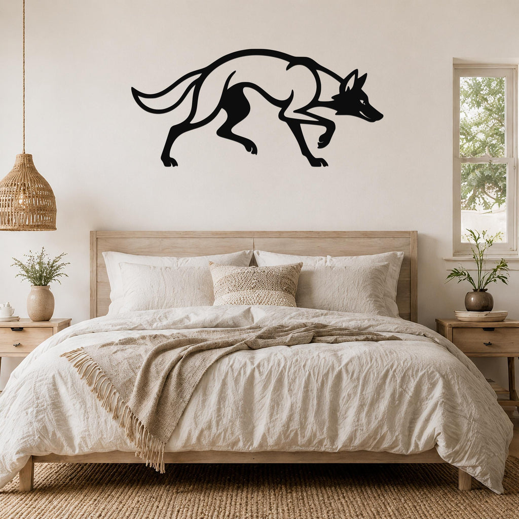 Black metal coyote wall art silhouette with motion-line cutouts, mounted above a bed in a neutral bedroom.