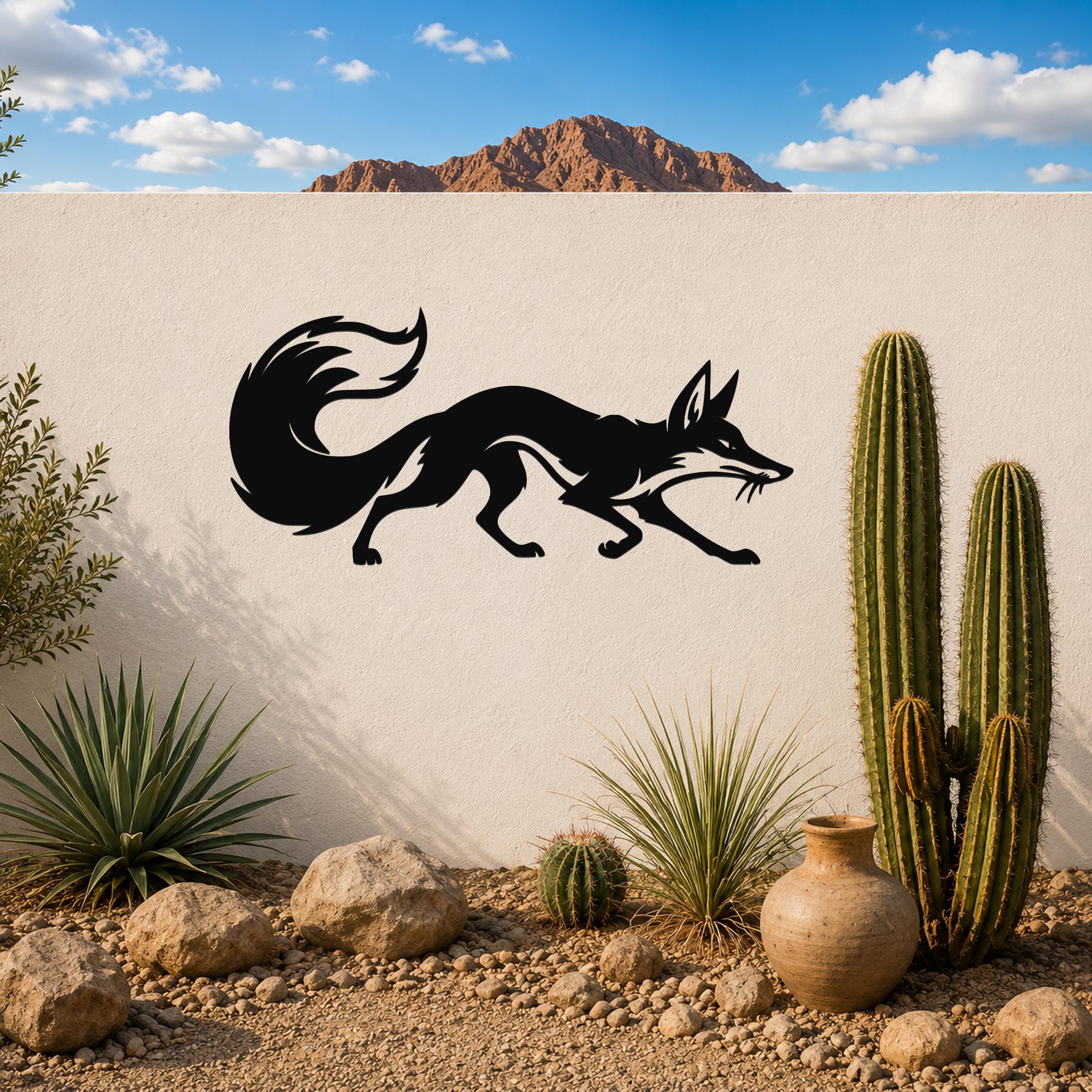 Black metal fox silhouette wall art with a curved tail and pointed ears, mounted on a white outdoor wall above a desert garden with cacti and rocks.