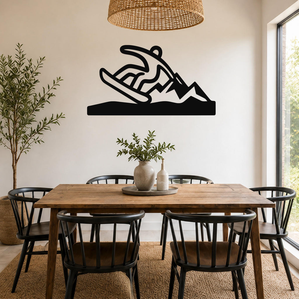 Black metal wall sculpture of a snowboarder in motion, mounted above a wooden dining table in a bright room.