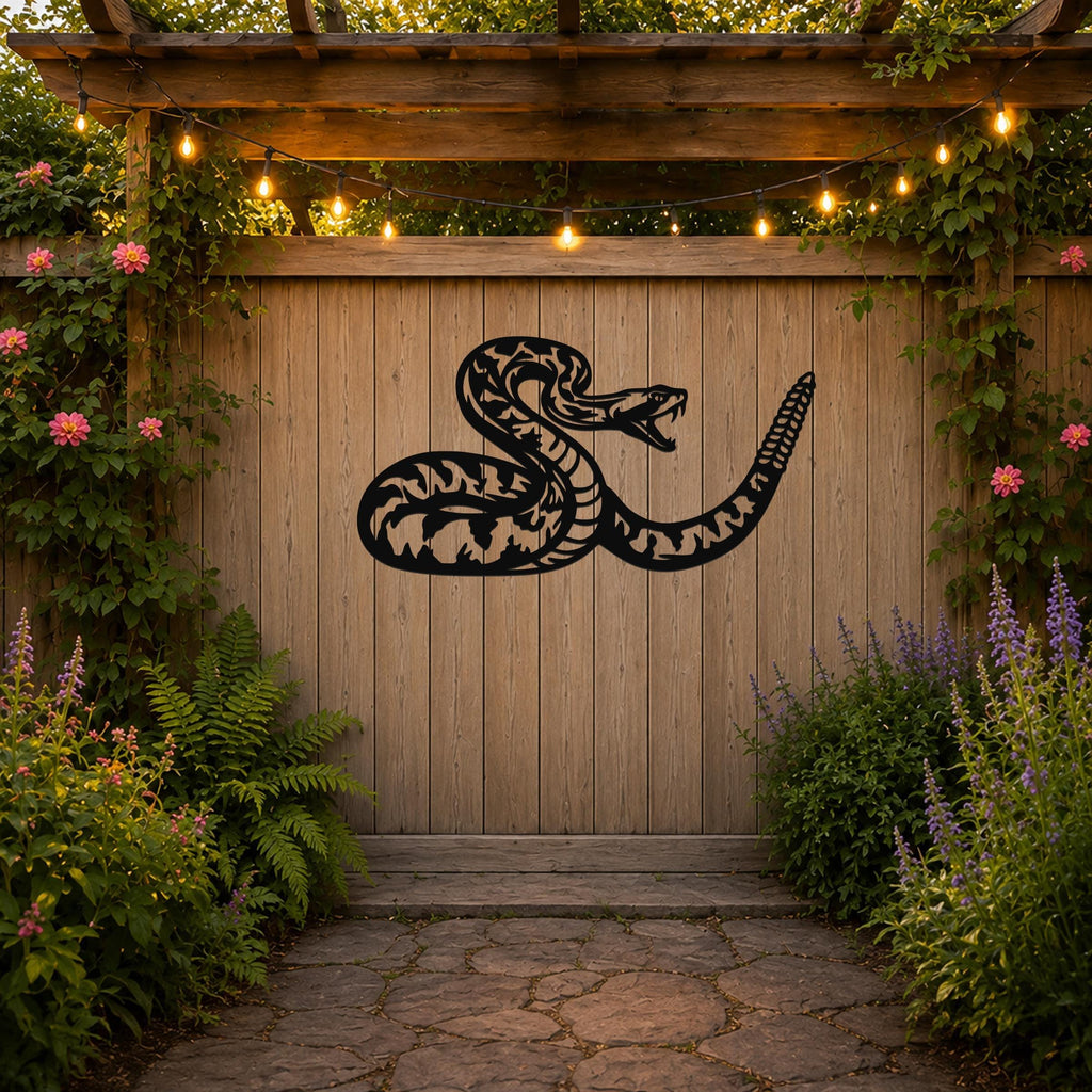 Black metal snake wall art with intricate internal cutouts, mounted on a wooden fence in a garden setting with string lights and flowering plants.
