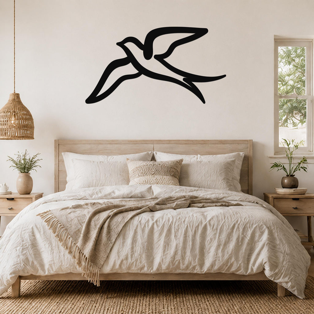 Black metal swallow bird wall art with flowing wing cutouts, mounted above a wooden bed in a neutral bedroom.