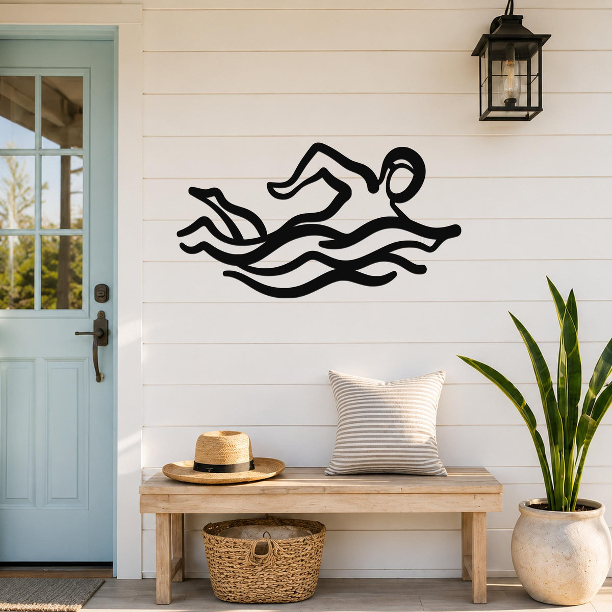 Black metal swimmer wall art with motion-line cutouts, mounted on a white shiplap wall above a wooden bench in a porch entryway.