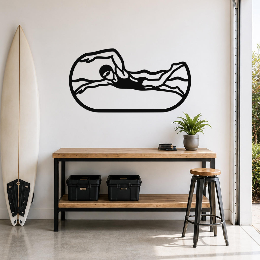 Black metal swimmer wall art with motion-line cutouts, mounted above a wooden console table in a bright room with a surfboard and plant.