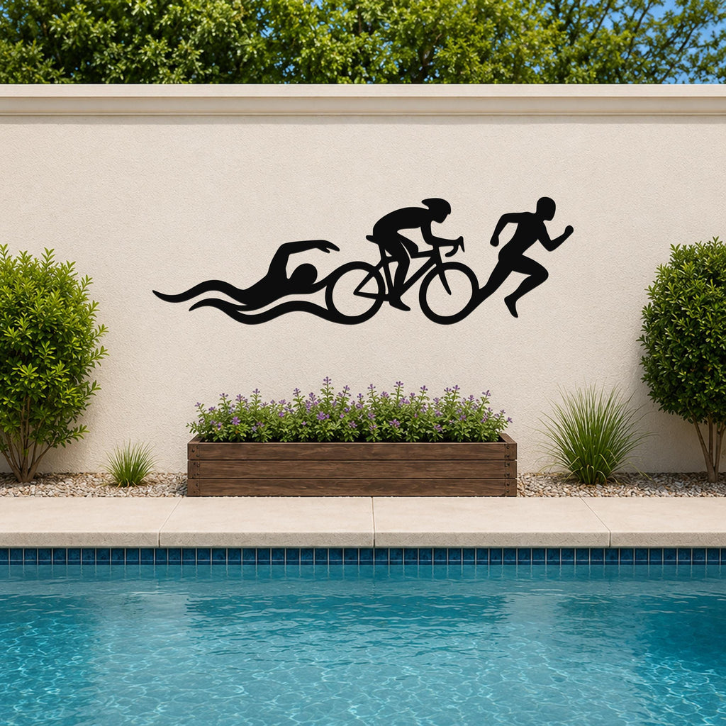 Black metal triathlon wall art with swim, bike, and run silhouettes and motion lines, mounted on an outdoor wall above a poolside planter.