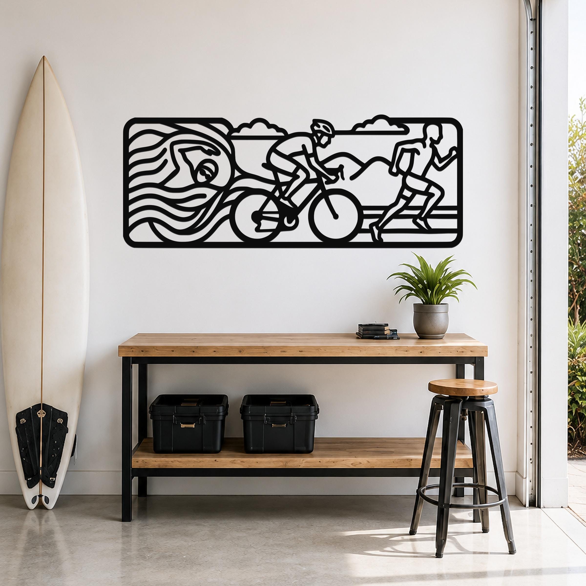 Black metal triathlon wall art with swim, bike, and run silhouettes, mounted above a wooden console table in a bright entryway.