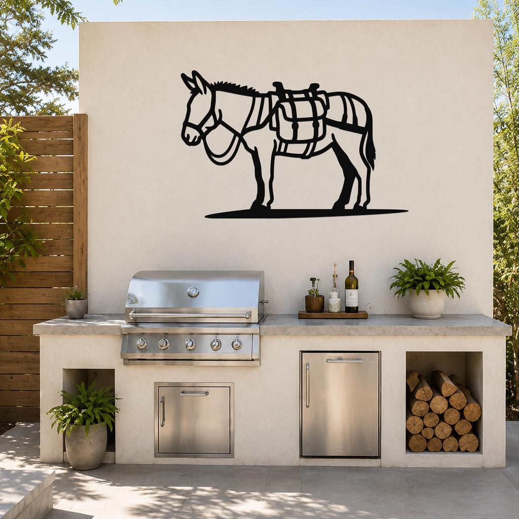 Black metal burro wall art with saddle cutout, mounted on an outdoor kitchen wall above a stainless steel grill.