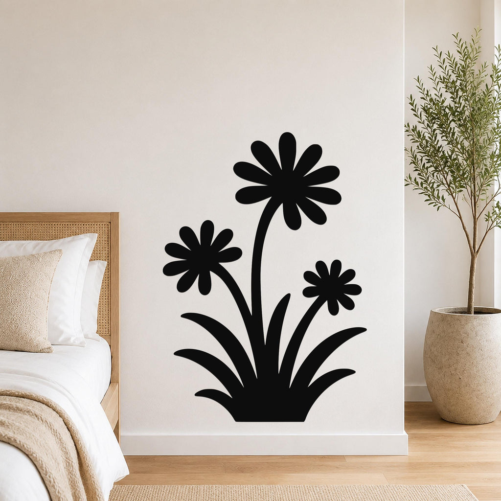 Black metal wall art featuring a silhouette of three daisy-like flowers with long stems and leaves, mounted on a bedroom wall above a bed.