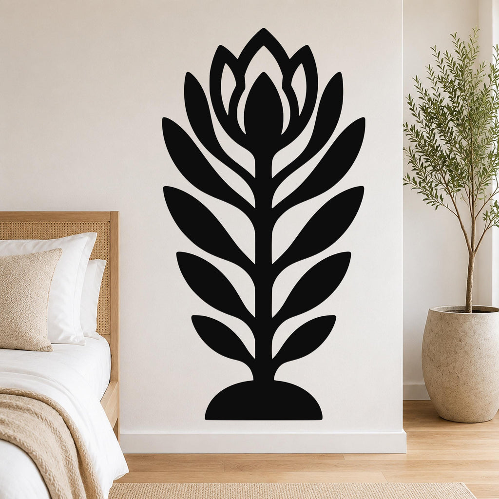 Black metal wall art in a stylized wildflower silhouette with layered petals and leaves, mounted on a bedroom wall above a bed.