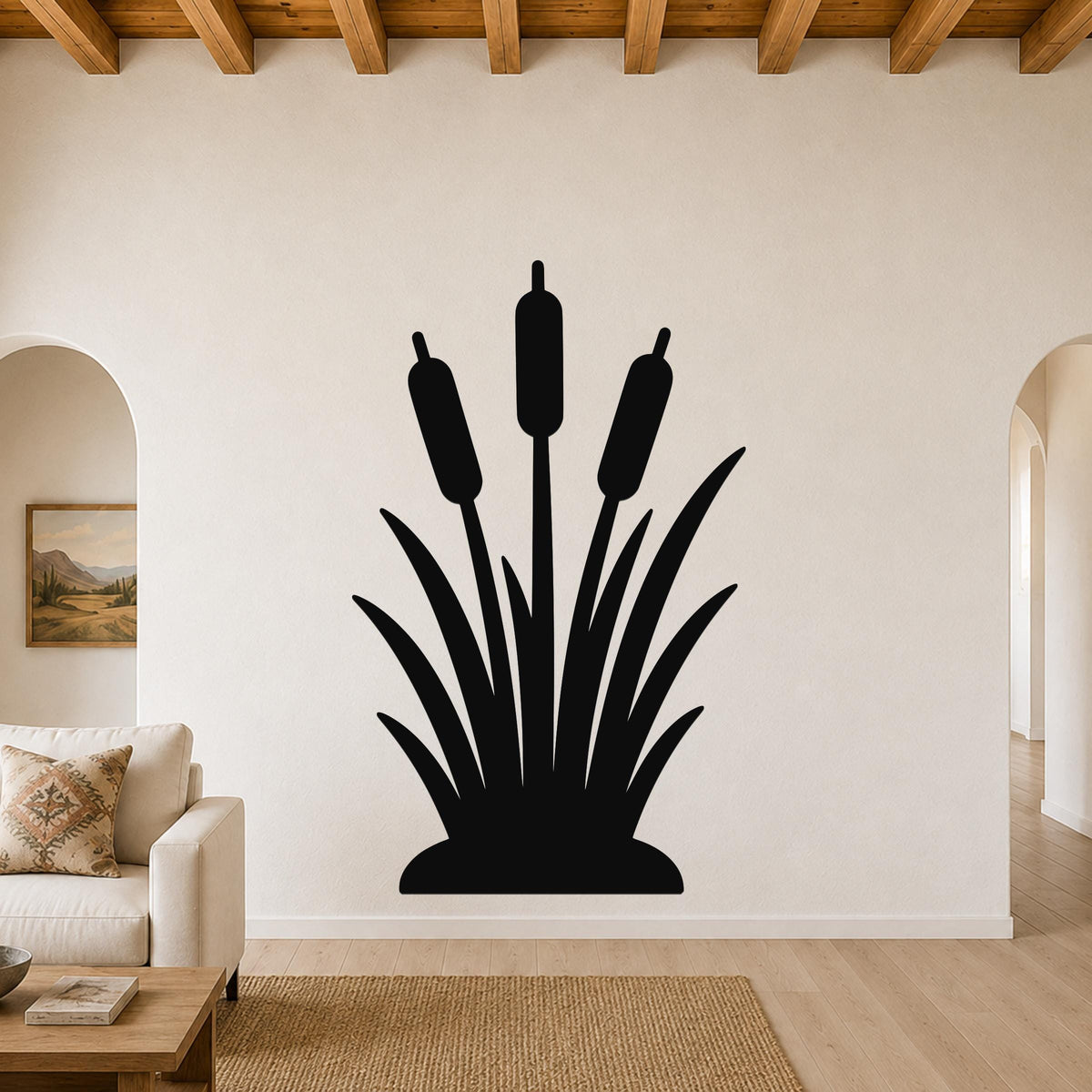 Black metal cattail wall art silhouette with three reed stalks and leafy base, mounted on a living room wall above a sofa.