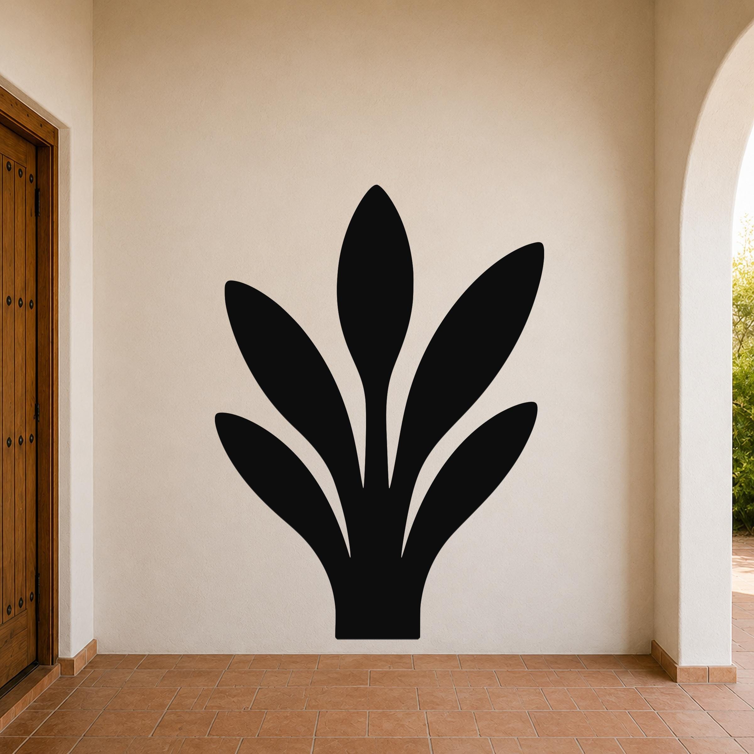 Black metal wall art in a snake plant silhouette, mounted on a beige outdoor wall above terracotta tile flooring.