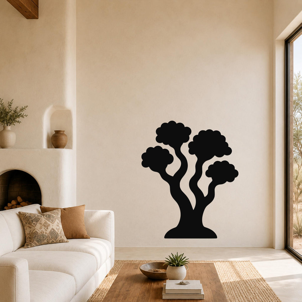Black metal tree wall art with a silhouette design of multiple curved trunks and cloud-like canopies, mounted on a living room wall above a sofa.