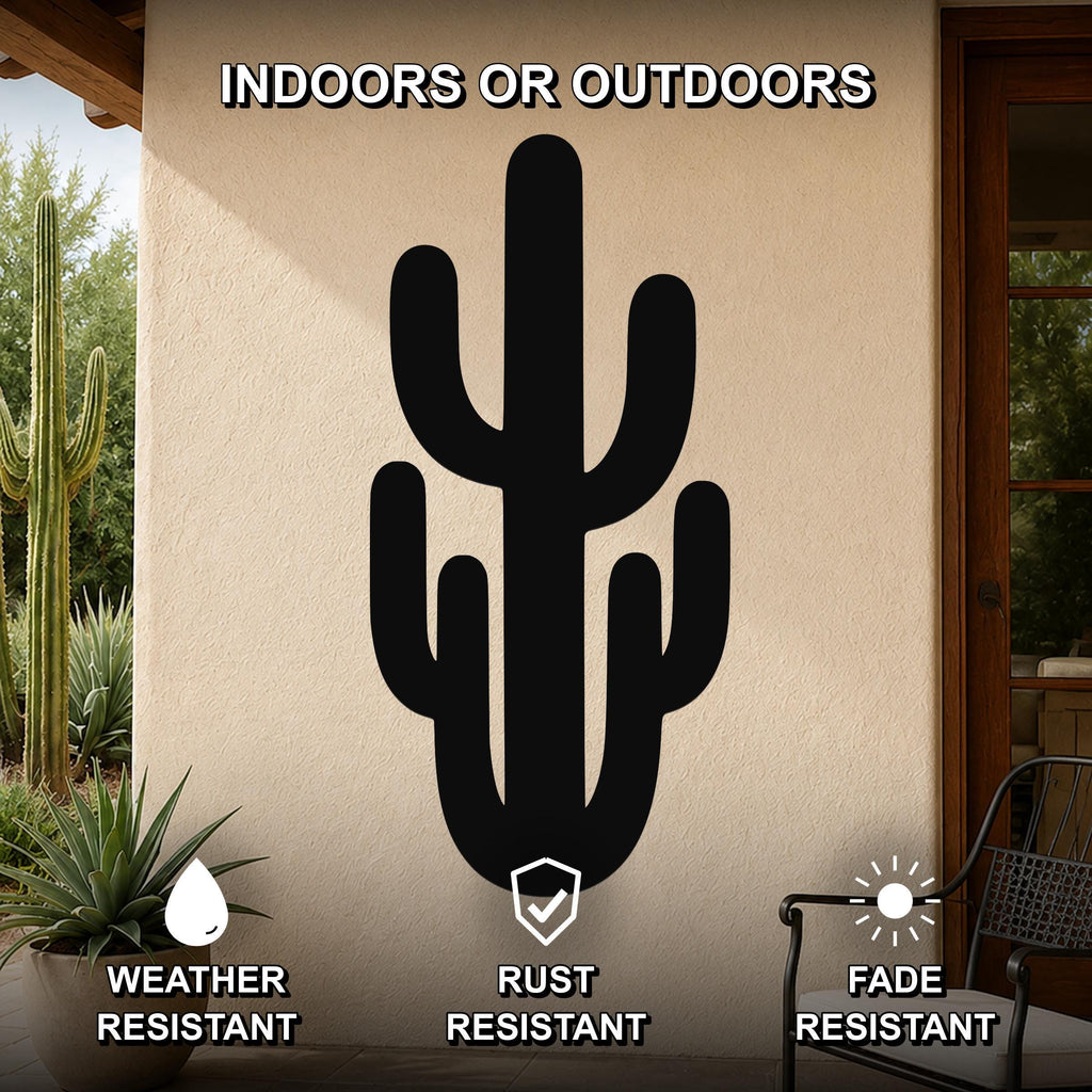 Black metal saguaro cactus wall art with cutout branches, mounted on an outdoor patio wall above a potted plant.