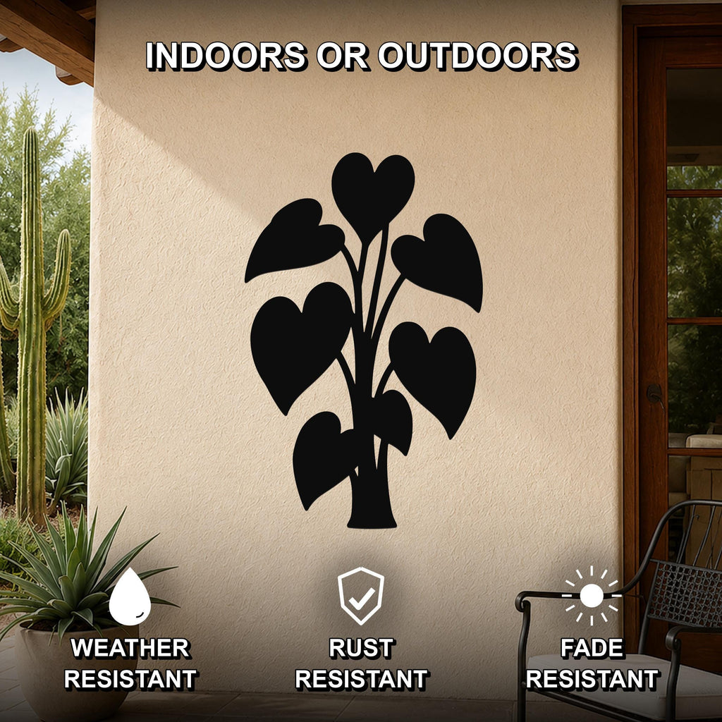 Black metal wall art featuring a heart-shaped leaf plant silhouette, mounted on an outdoor patio wall with cactus and potted plant nearby.