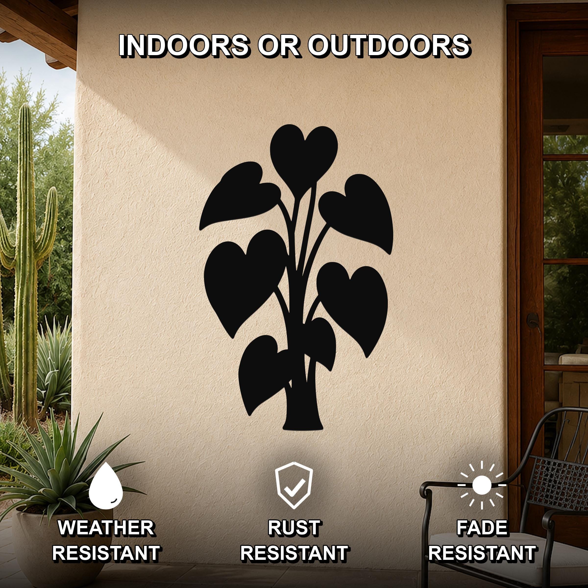Black metal wall art featuring a heart-shaped leaf plant silhouette, mounted on an outdoor patio wall with cactus and potted plant nearby.