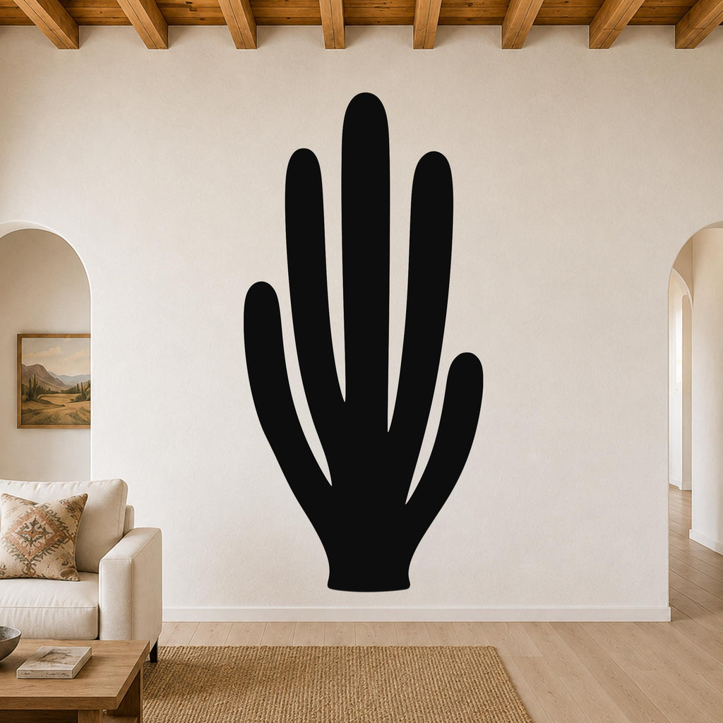 Black metal wall art in the shape of an organ pipe cactus, mounted on a living room wall above a sofa.