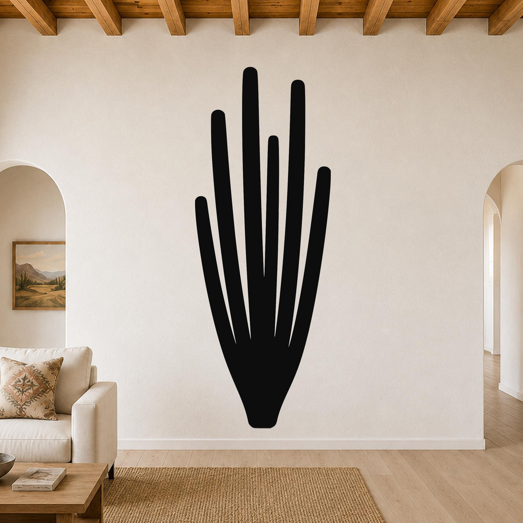 Black metal wall art in the shape of an organ pipe cactus with vertical spines, mounted on a living room wall above a sofa.