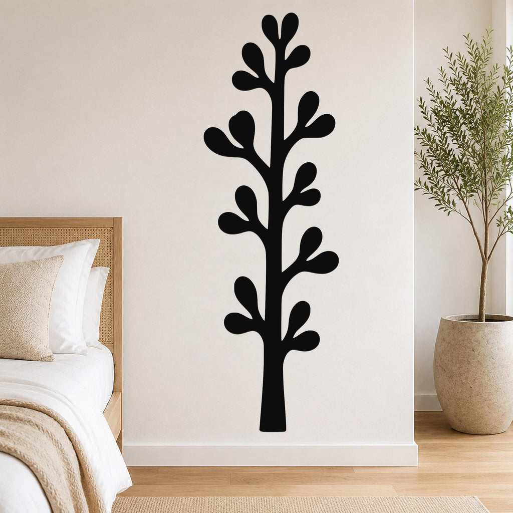 Black metal wall art in a stylized olive branch silhouette, mounted on a white bedroom wall above a bed.