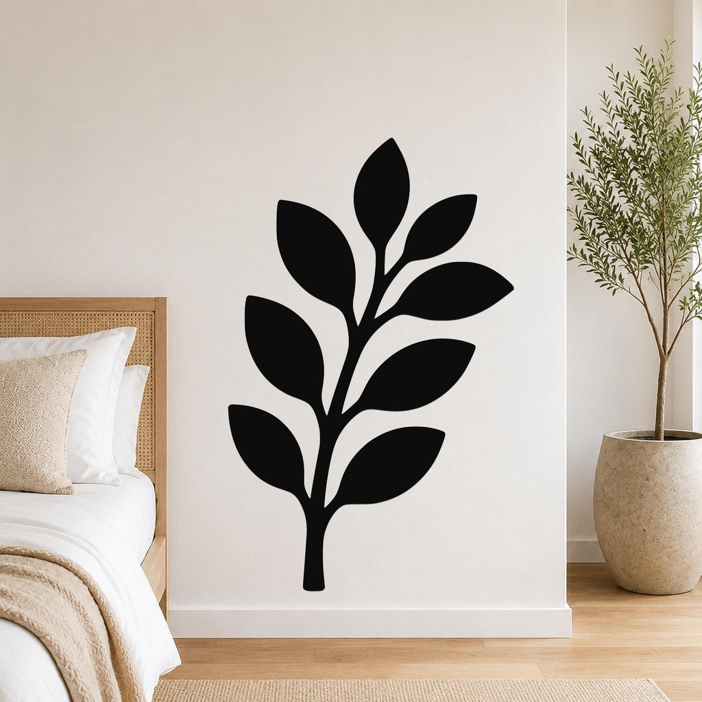 Black metal olive branch wall art with leaf cutouts, mounted on a white bedroom wall above a bed.
