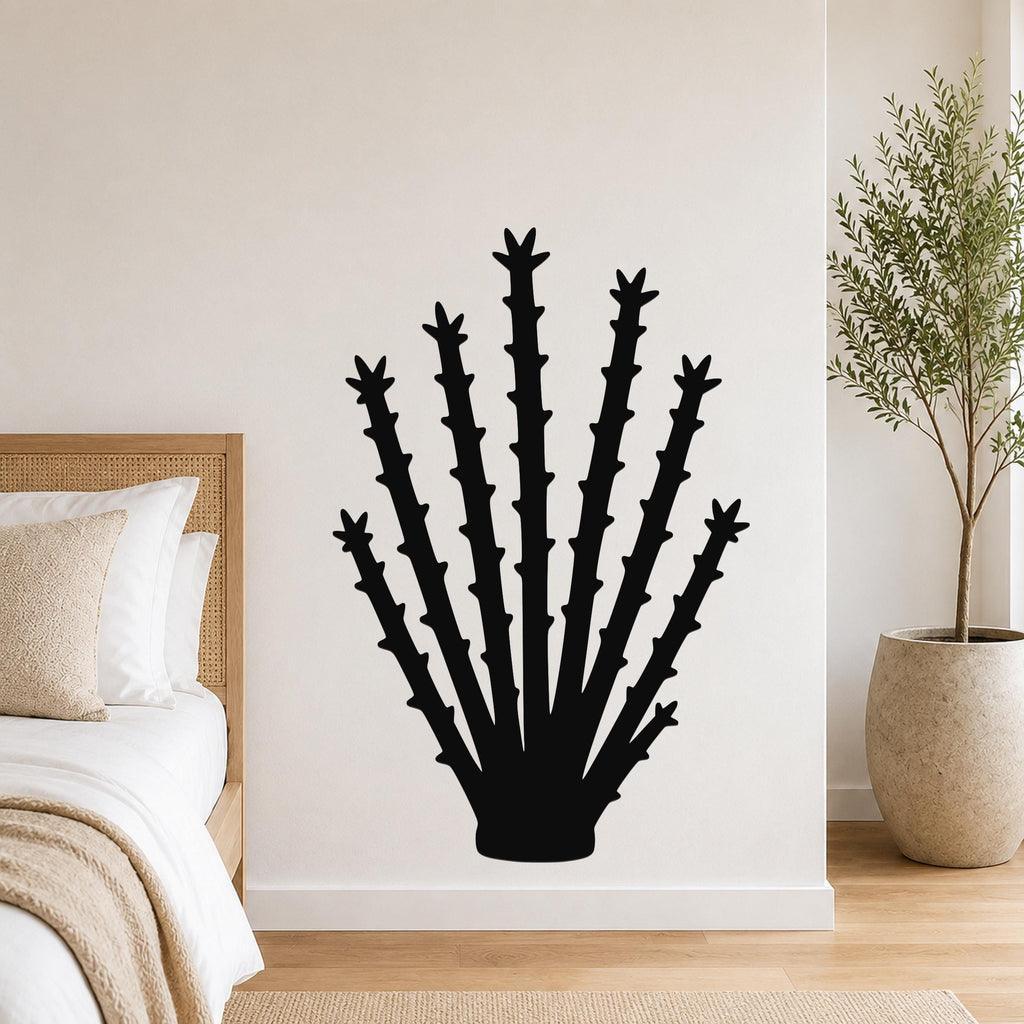 Black metal ocotillo wall art silhouette with spiky branches, mounted on a bedroom wall above a bed.