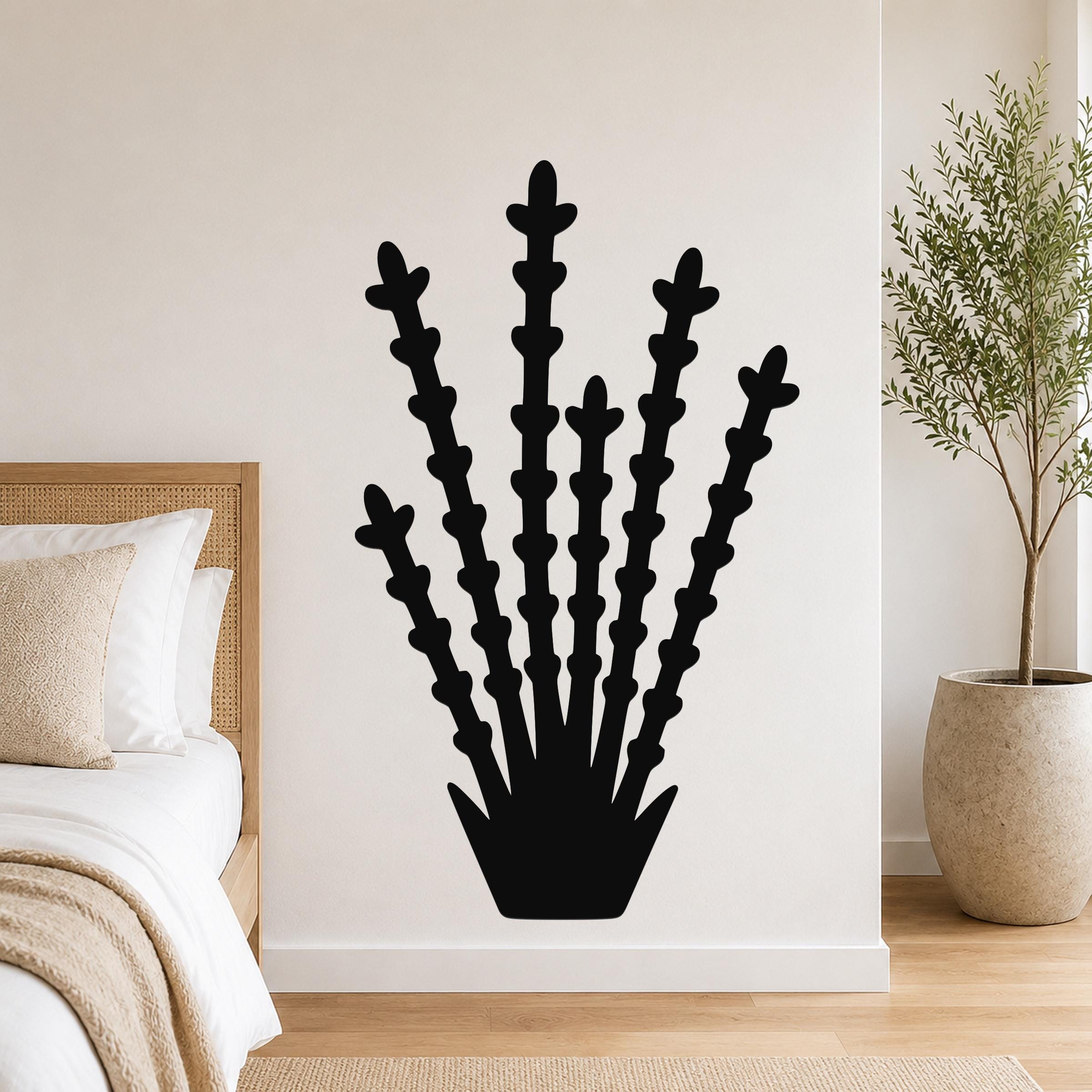Black metal ocotillo wall art with branching stem cutouts, mounted on a bedroom wall above a bed.