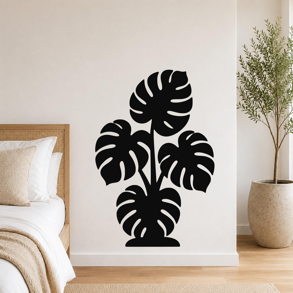 Black metal wall art featuring a monstera plant silhouette with cutout leaves, mounted on a bedroom wall above a bed.