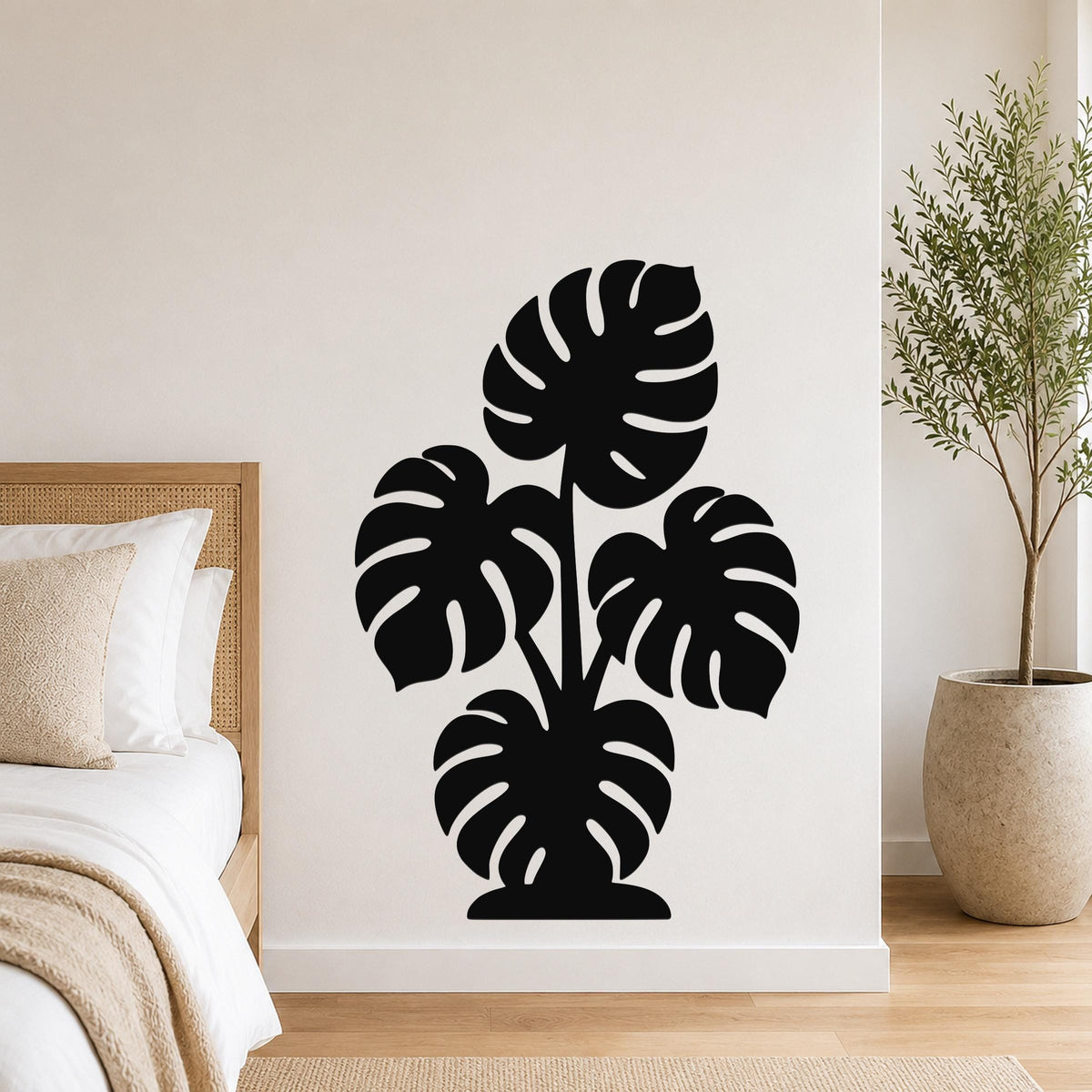 Black metal wall art featuring a monstera plant silhouette with cutout leaves, mounted on a bedroom wall above a bed.
