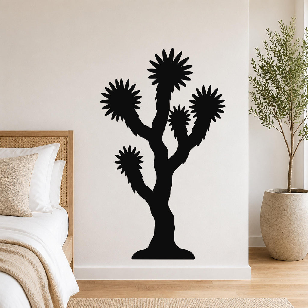 Black metal Joshua tree wall art with starburst-shaped branches, mounted on a white bedroom wall above a bed.