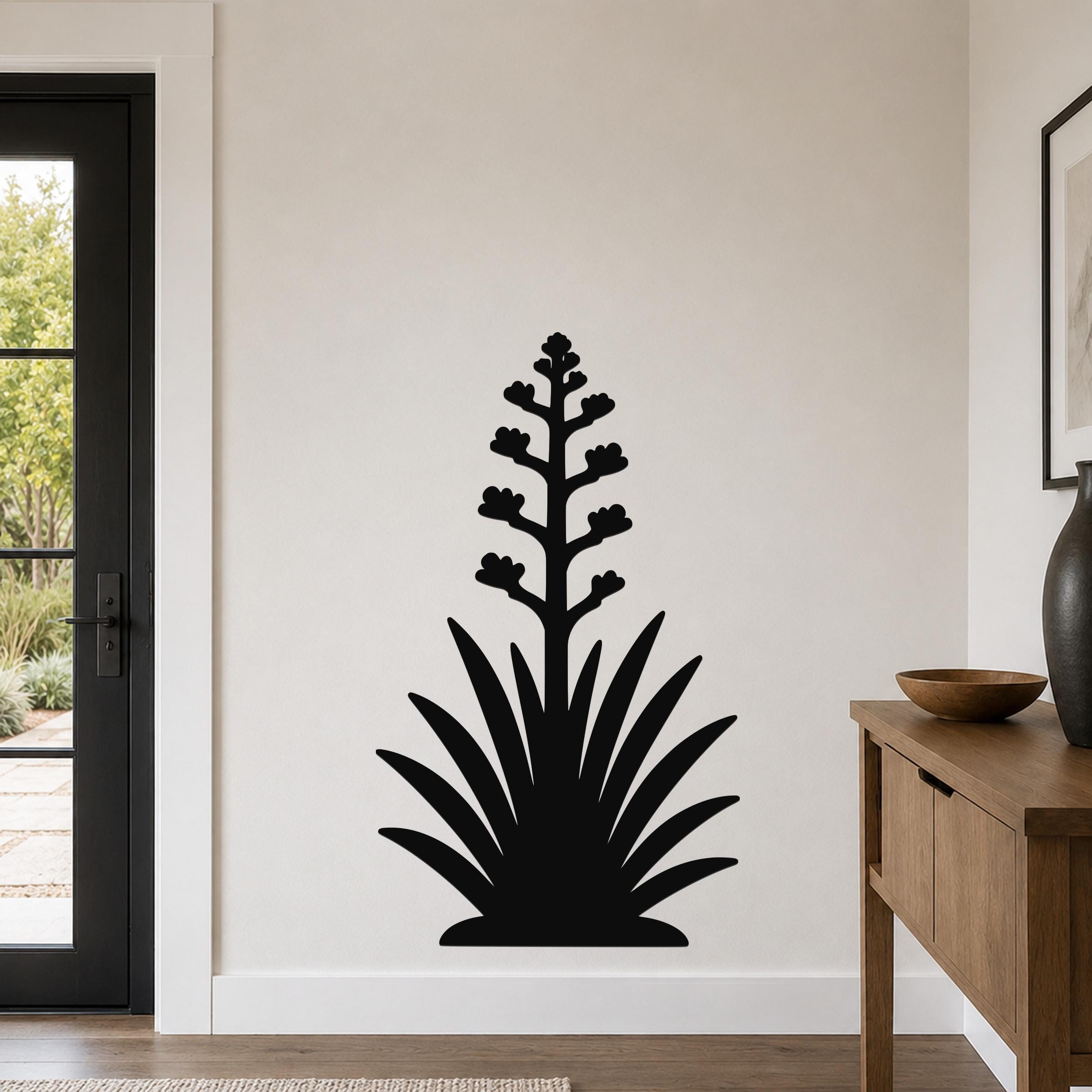 Black metal agave wall art with a blooming flower silhouette, mounted on a light-colored wall in a modern entryway.