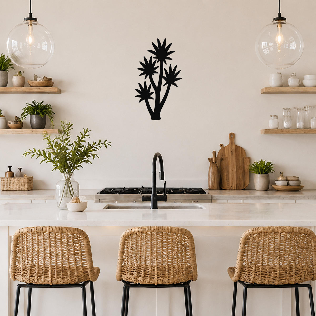 Black metal yucca wall art with layered leaf cutouts, mounted on a kitchen wall above a counter with wicker stools.