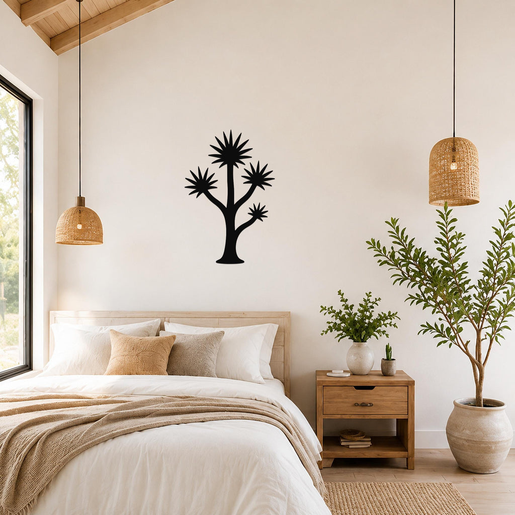 Black metal wall art in a yucca tree silhouette with starburst-shaped fronds, mounted on a bedroom wall above a bed.