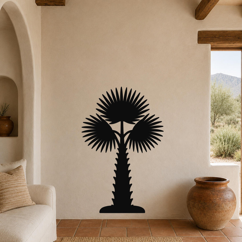 Black metal palm tree wall art with fan-shaped fronds and a textured trunk, mounted on a beige stucco wall in a living room with terracotta flooring and wooden beams.