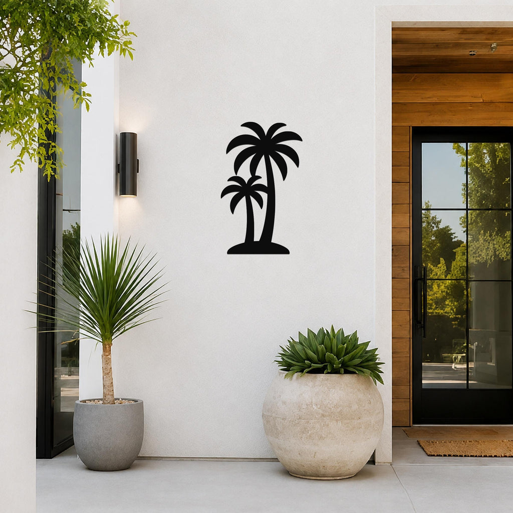 Black metal twin palm trees wall art silhouette mounted on a white exterior wall beside a glass door and potted plants.