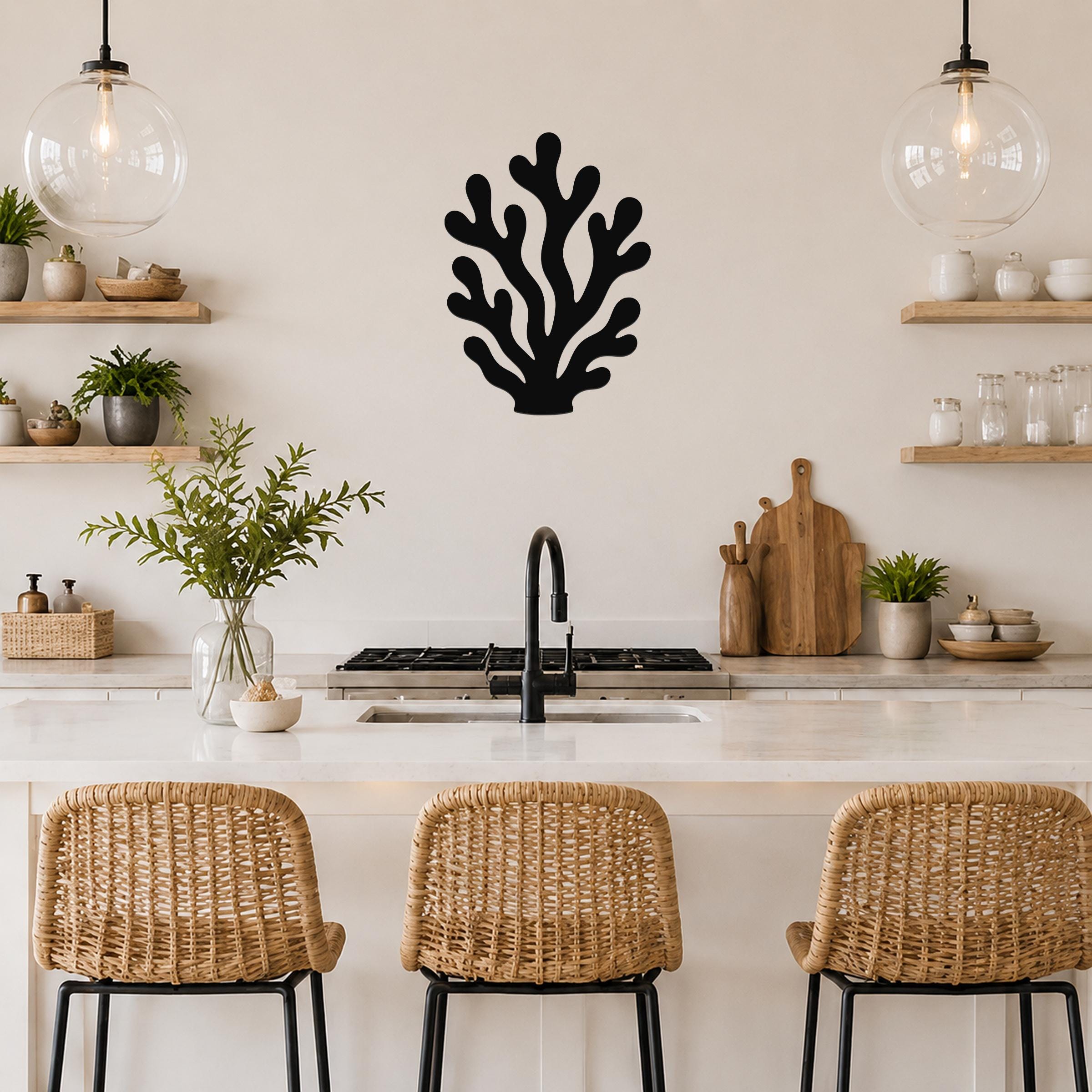 Black metal coral wall art with branching cutouts, mounted on a kitchen wall above a counter with wicker bar stools.