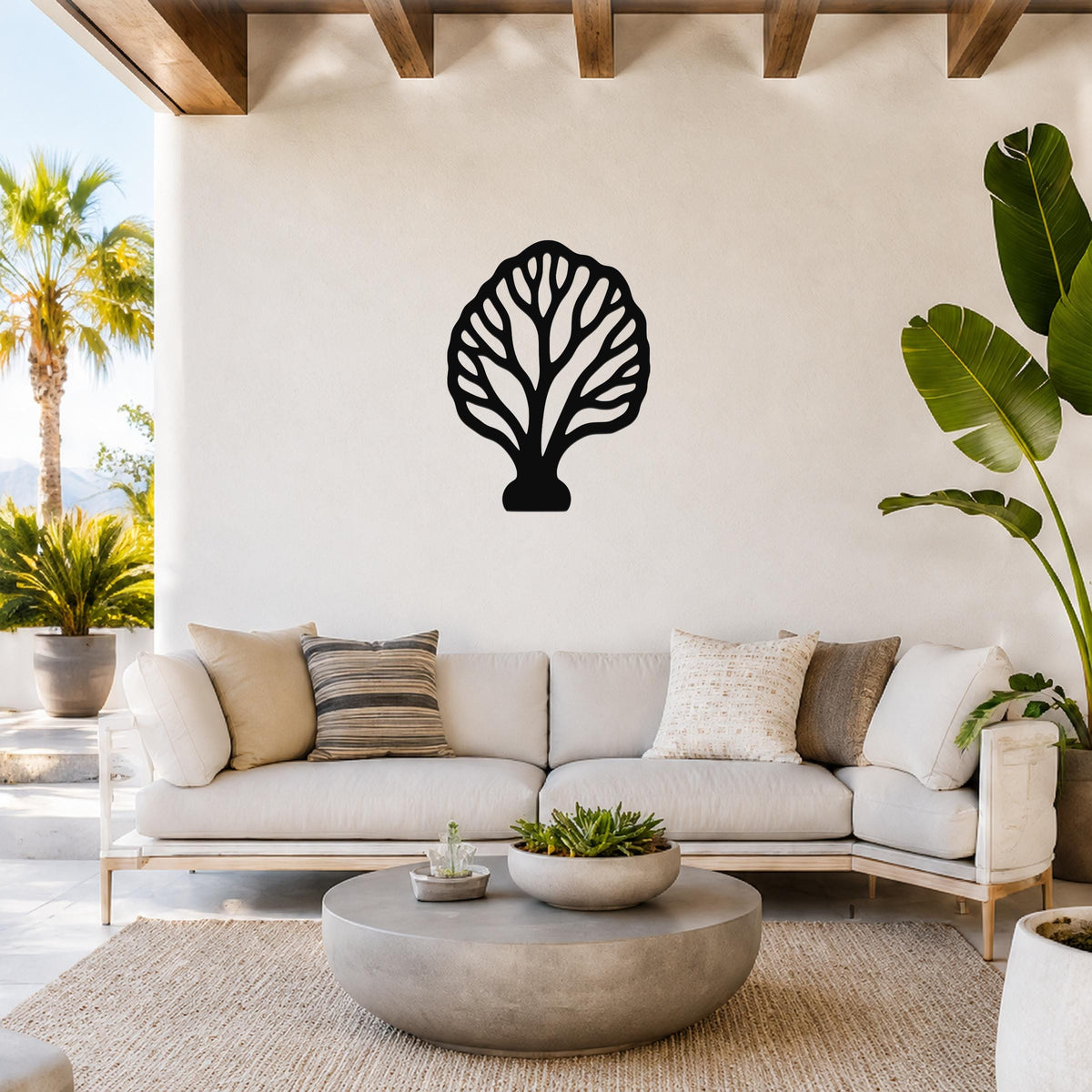 Black metal fan coral wall art with intricate branch cutouts, mounted on a white wall above a light-colored sofa in a bright living room.