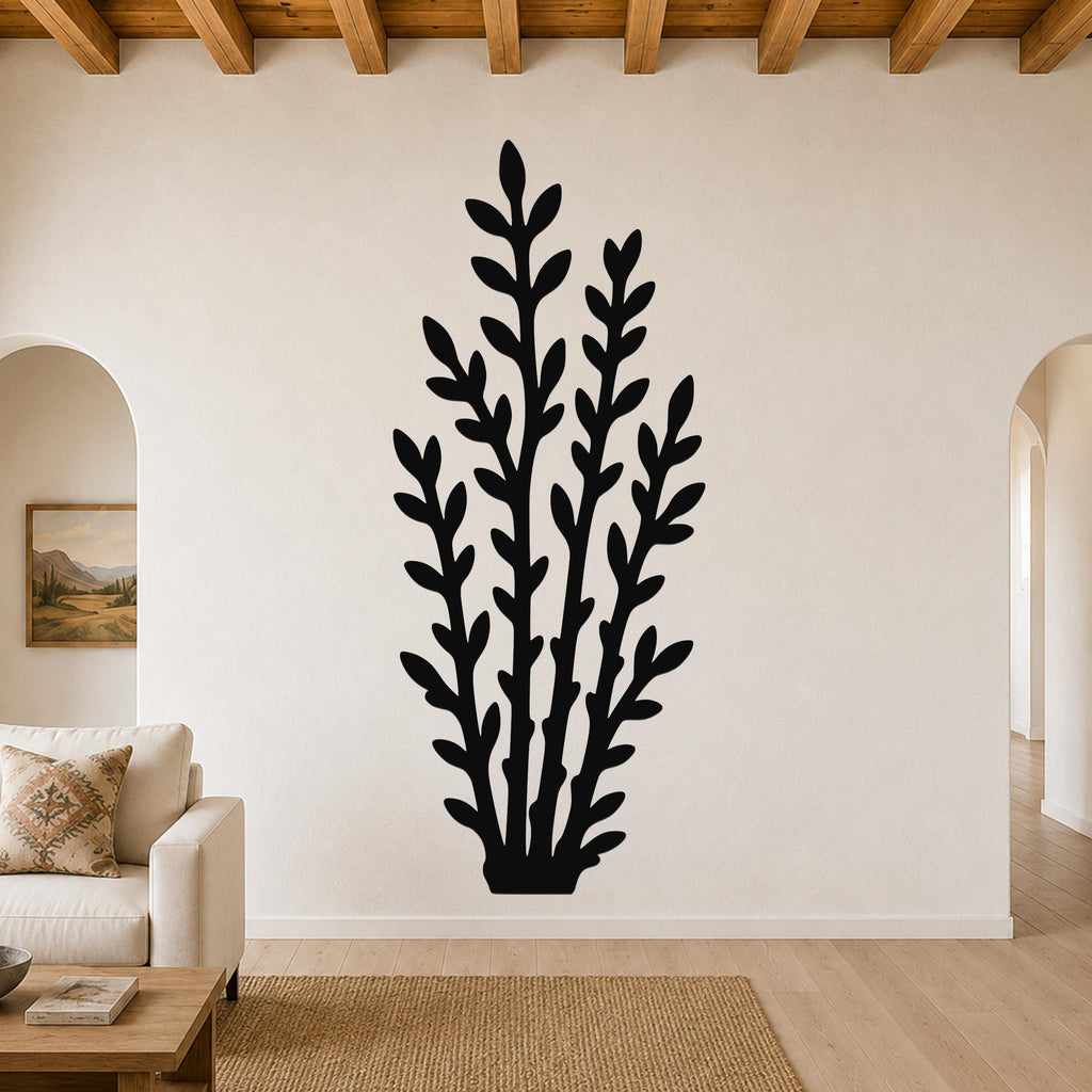 Black metal wall art in a leafy branch silhouette, mounted on a living room wall above a sofa.