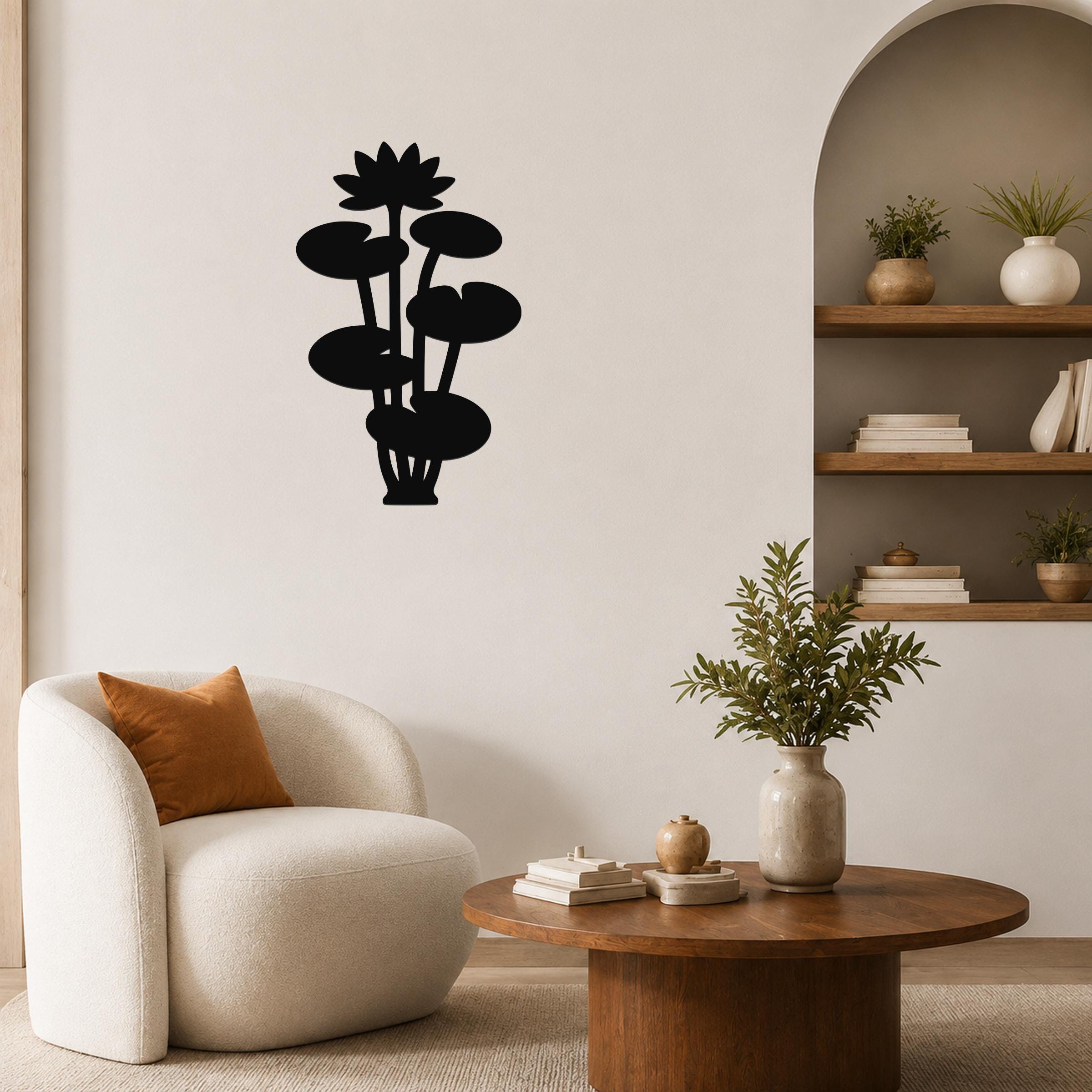 Black metal lotus water lily wall art with layered flower and leaf cutouts, mounted on a living room wall above a round wooden coffee table.