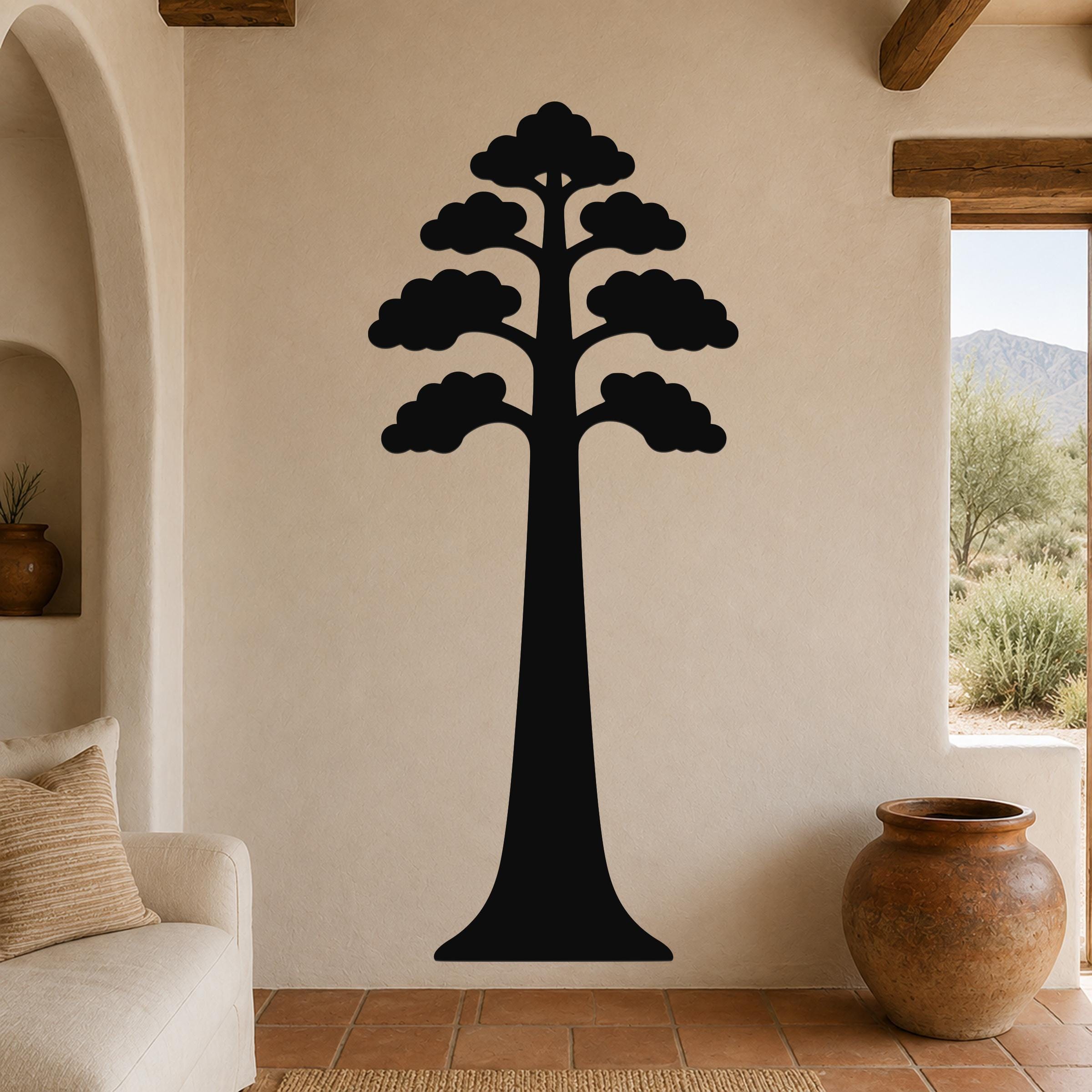Black metal sequoia tree wall art with layered canopy cutouts, mounted on a beige living room wall above a sofa.