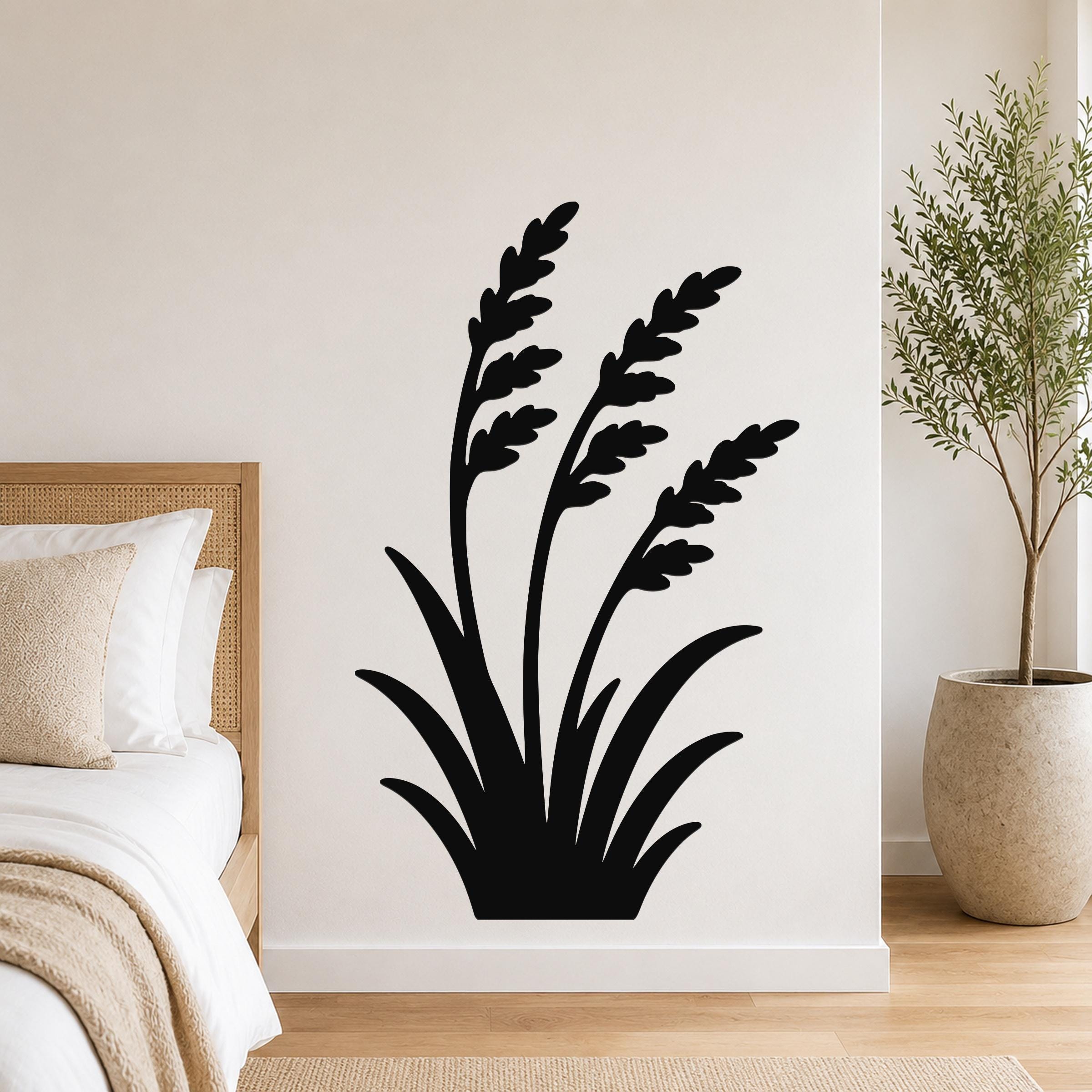 Black metal wall art in a wild grass silhouette design, mounted on a bedroom wall above a bed with a woven headboard.