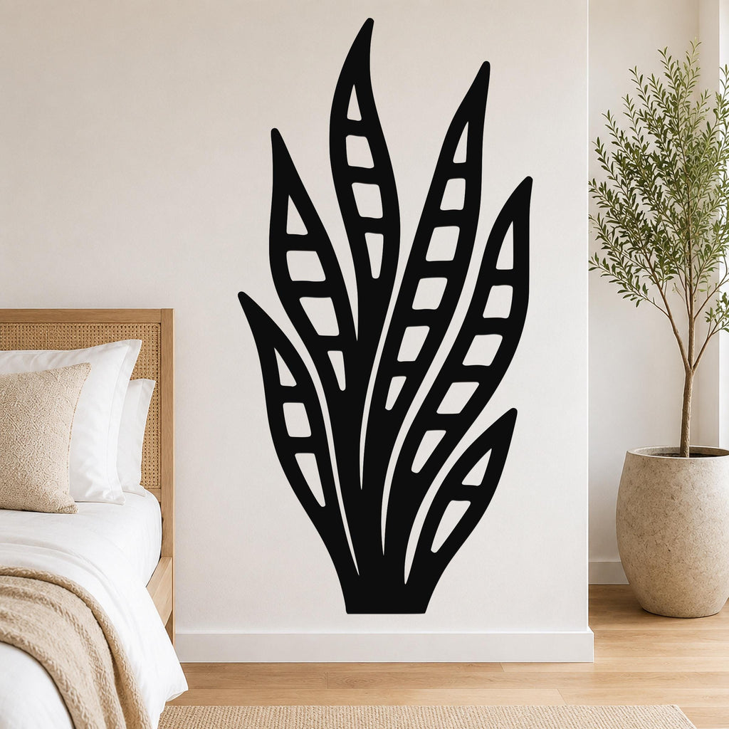 Black metal wall art in a snake plant silhouette with internal cutout details, mounted on a bedroom wall above a bed.