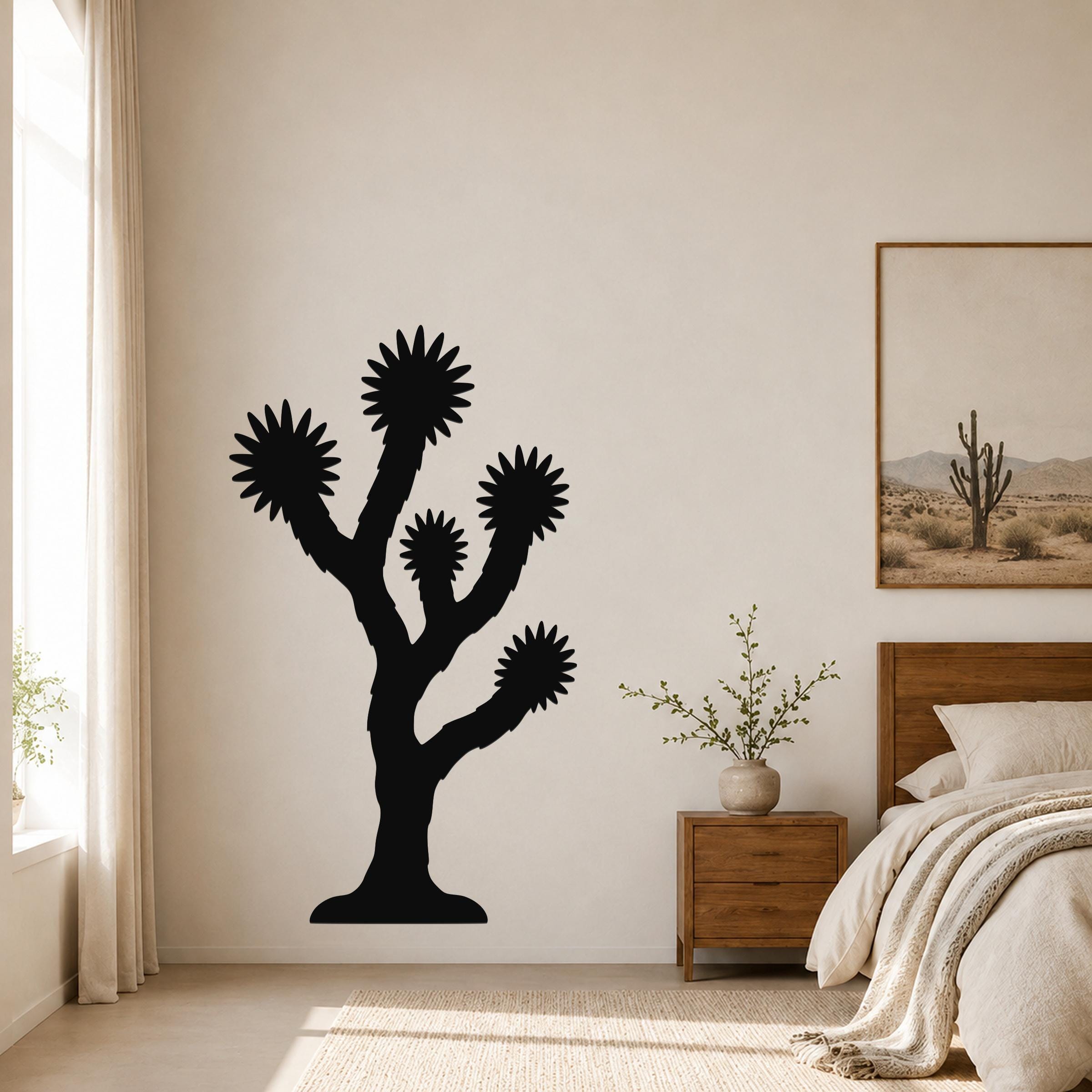 Black metal Joshua tree wall art with starburst-shaped branches, mounted on a bedroom wall above a wooden nightstand.
