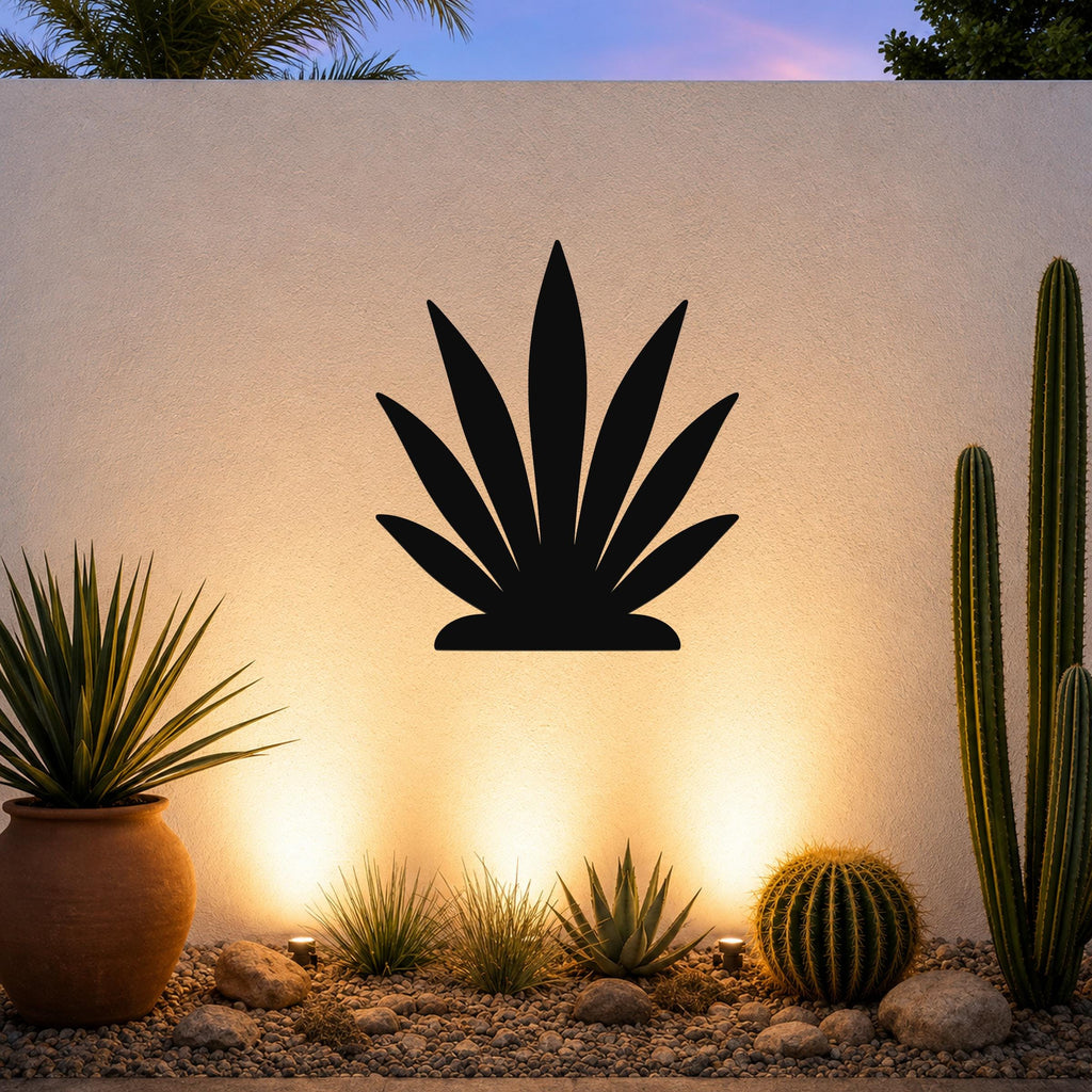 Black metal agave wall art silhouette mounted on a textured outdoor wall above a desert garden with cacti and warm uplighting.