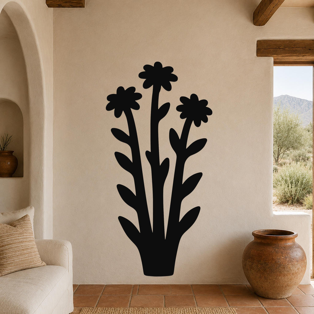 Black metal wall art featuring a silhouette of three wildflowers with long stems and leaves, mounted on a beige living room wall above a sofa.