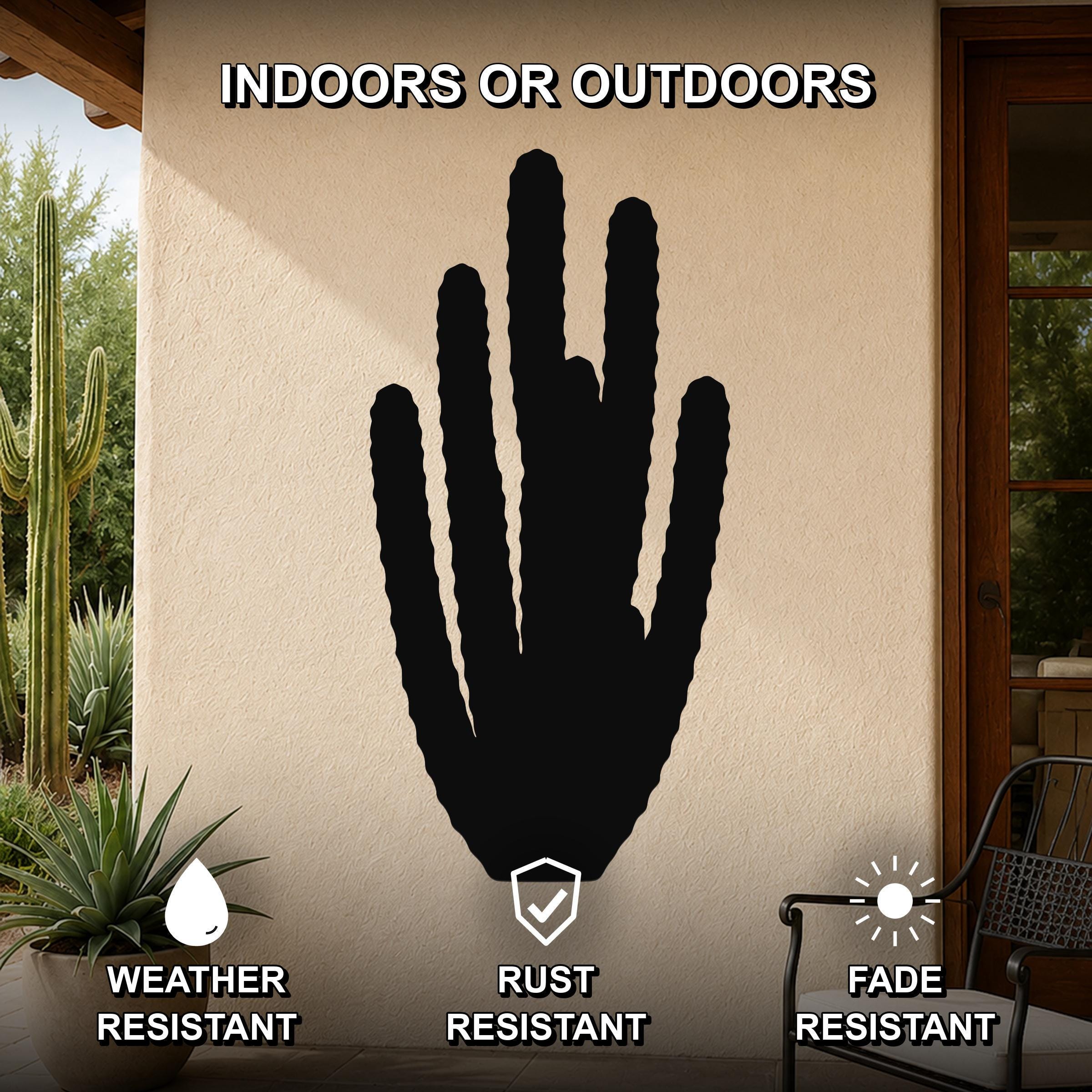Black metal organ pipe cactus wall art with vertical ribbed cutouts, mounted on an outdoor patio wall above a potted plant.