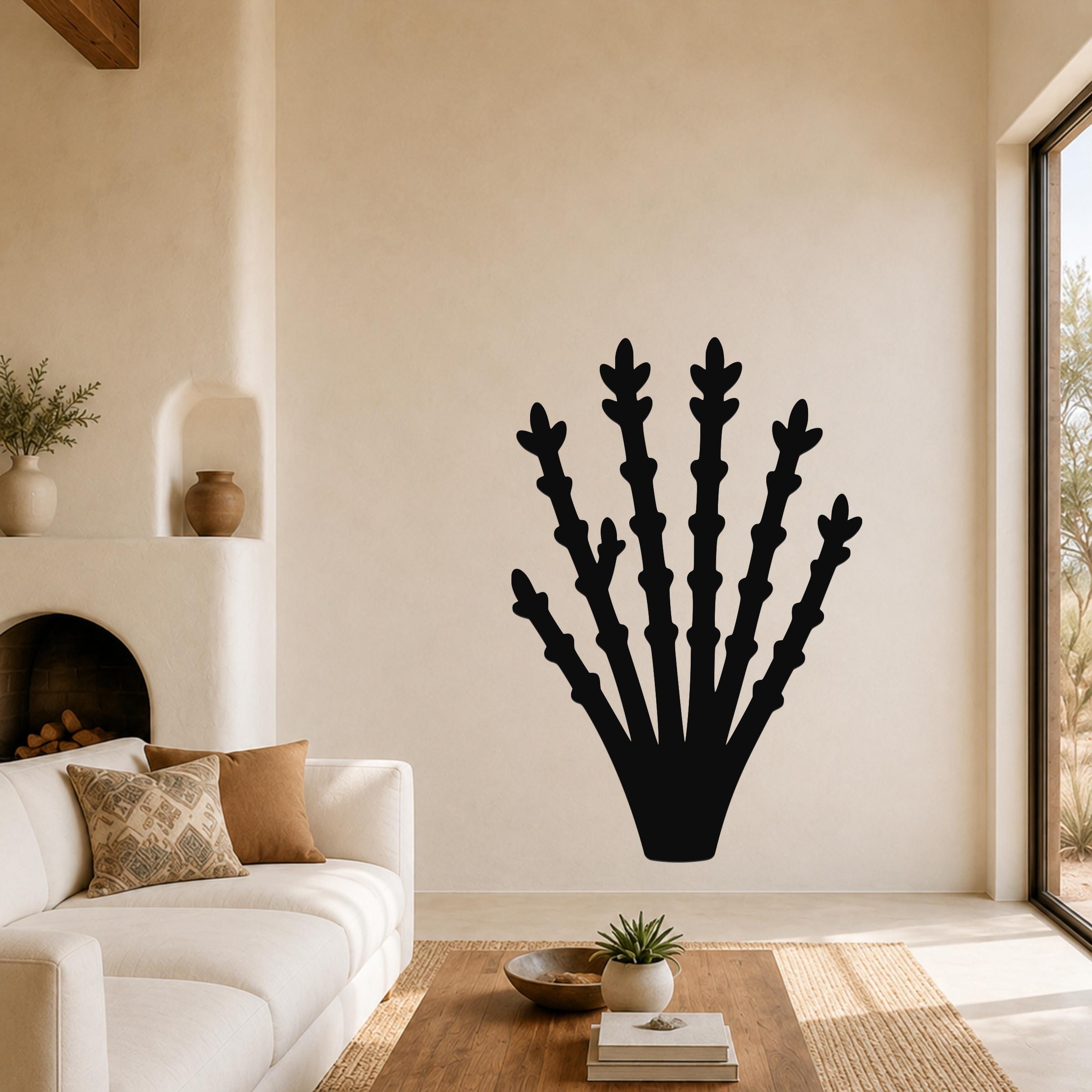 Black metal ocotillo wall art with branching cutouts, mounted on a living room wall above a sofa.