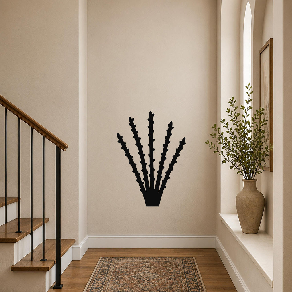 Black metal ocotillo wall art silhouette with spiky branches, mounted on a beige hallway wall near a staircase and window.