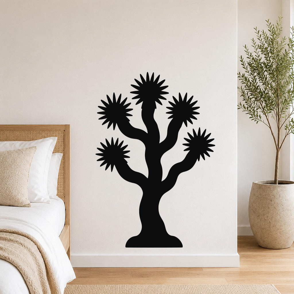 Black metal Joshua tree wall art with starburst-shaped branches, mounted on a bedroom wall above a bed.