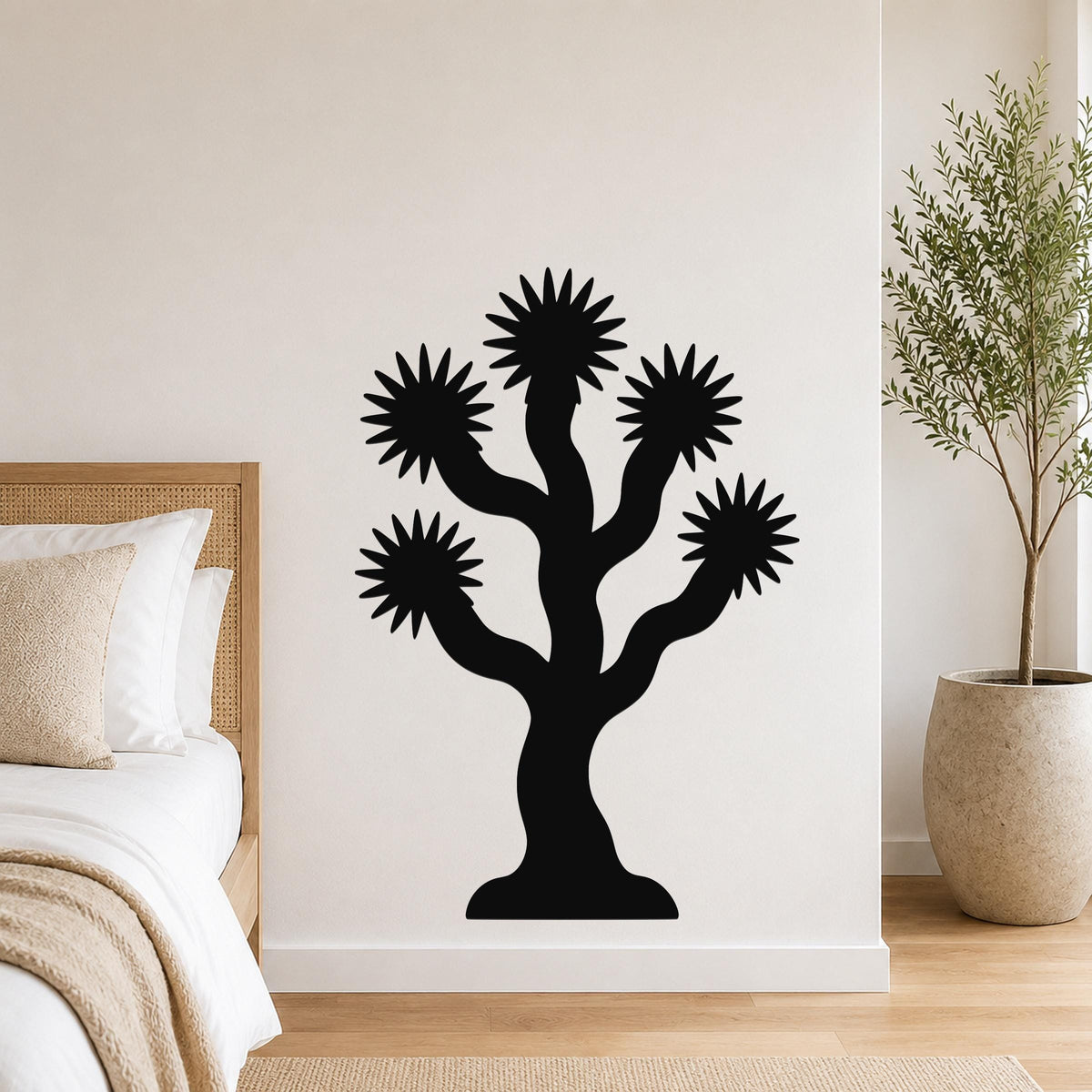 Black metal Joshua tree wall art with starburst-shaped branches, mounted on a bedroom wall above a bed.