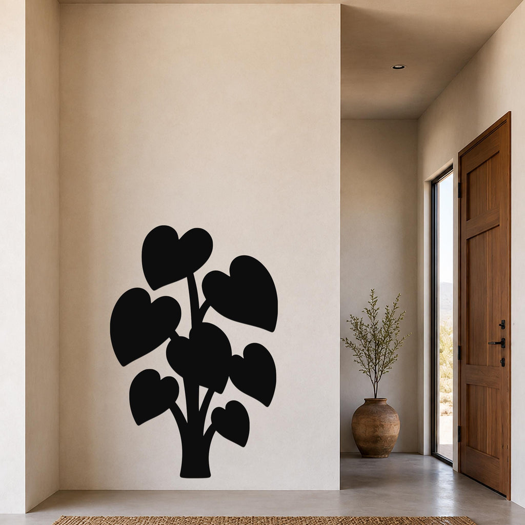 Black metal wall art in the silhouette of an elephant ear plant with heart-shaped leaves, mounted on a beige wall in a modern entryway.