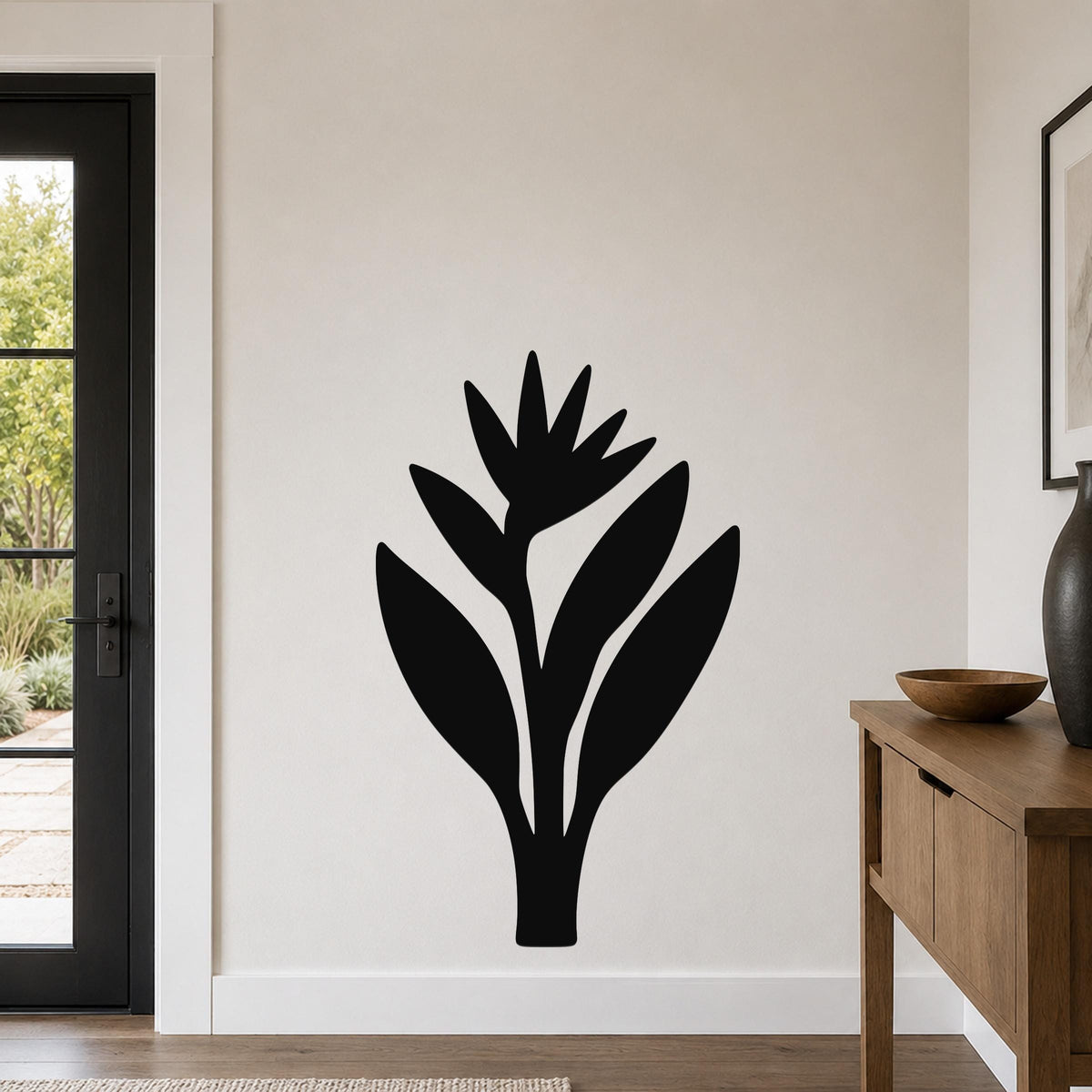 Black metal Bird of Paradise wall art with a silhouette cutout design, mounted on a light-colored wall in a modern entryway.